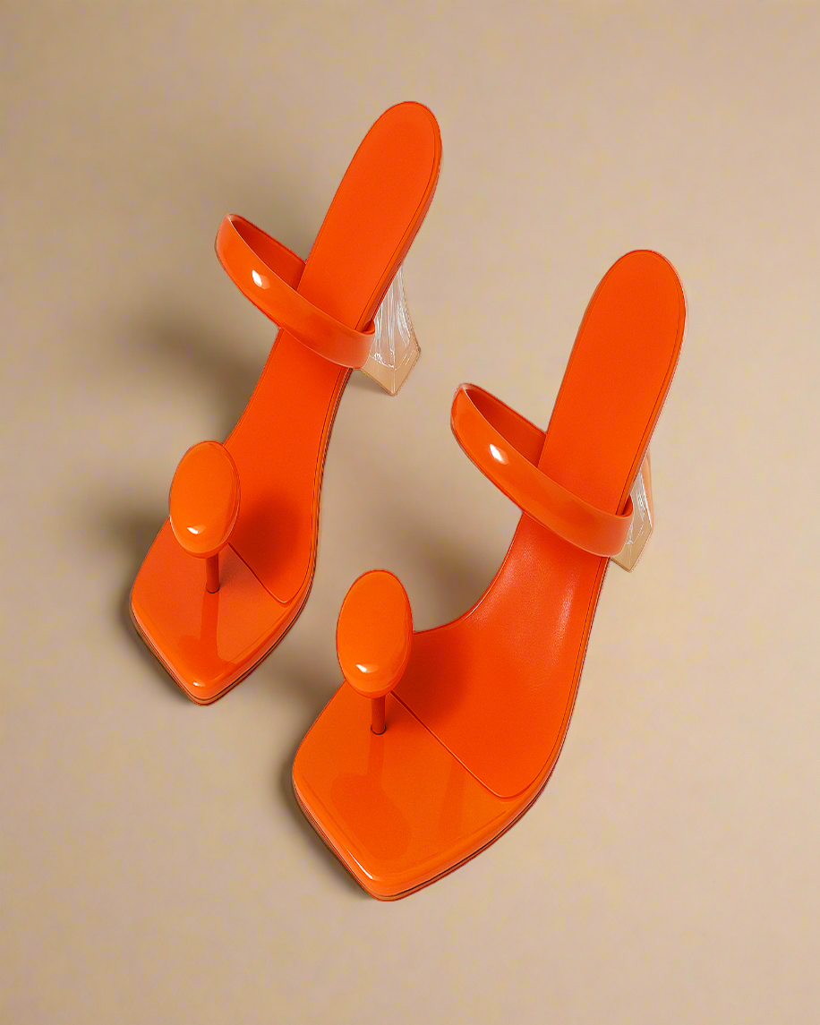 Pair of orange high-heeled shoes on a white background