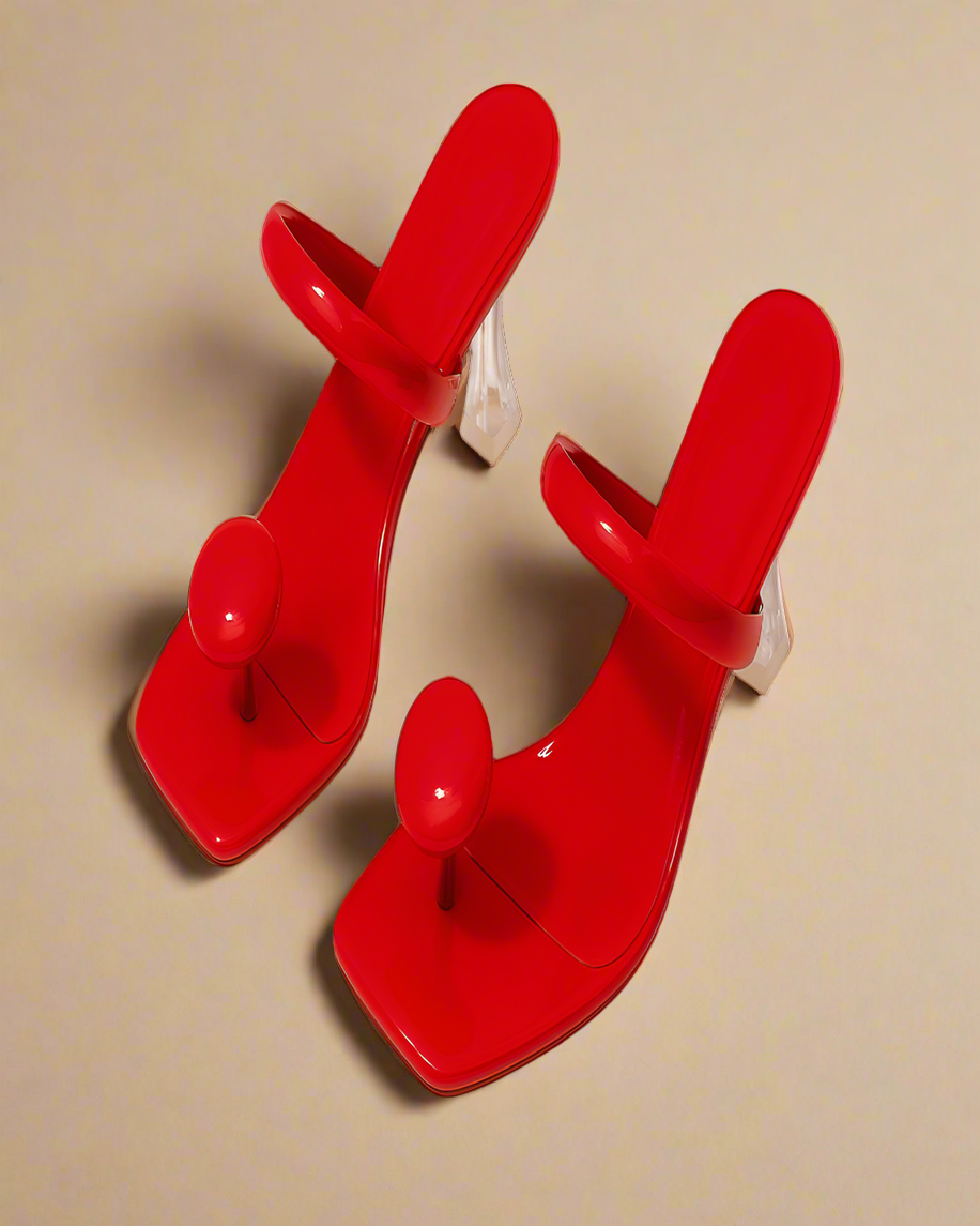 Pair of red high-heeled shoes with spherical designs on a white background