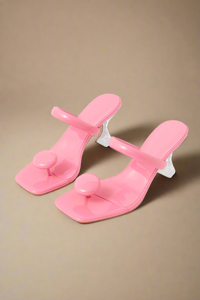 Pair of pink sandals with clear straps on a white background